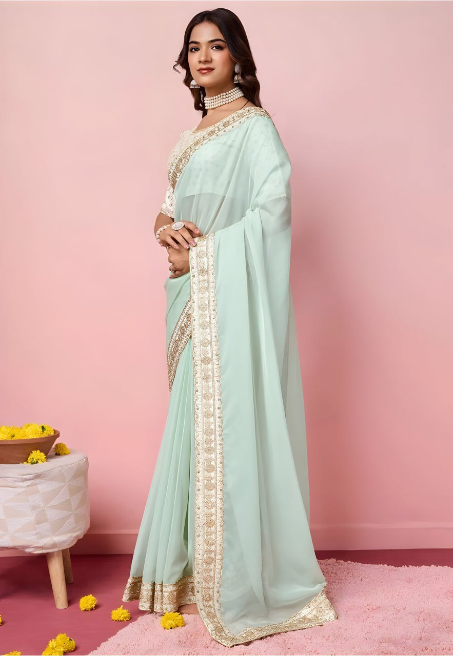 Woman wearing a light blue saree with gold border on a pink background