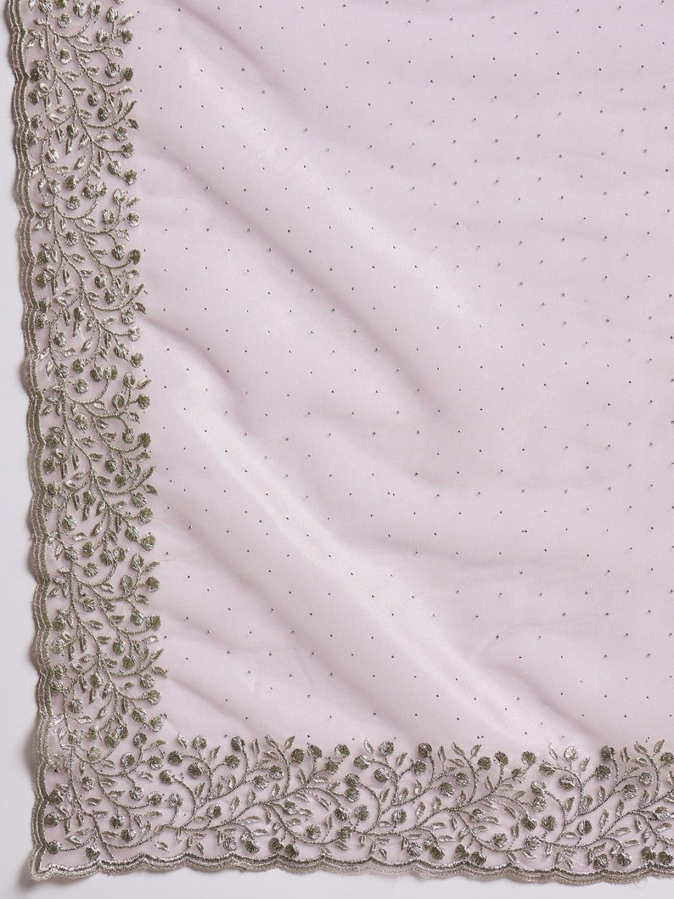 Close-up of pink net saree fabric with hotfix work, cutwork border, and stone embellishments