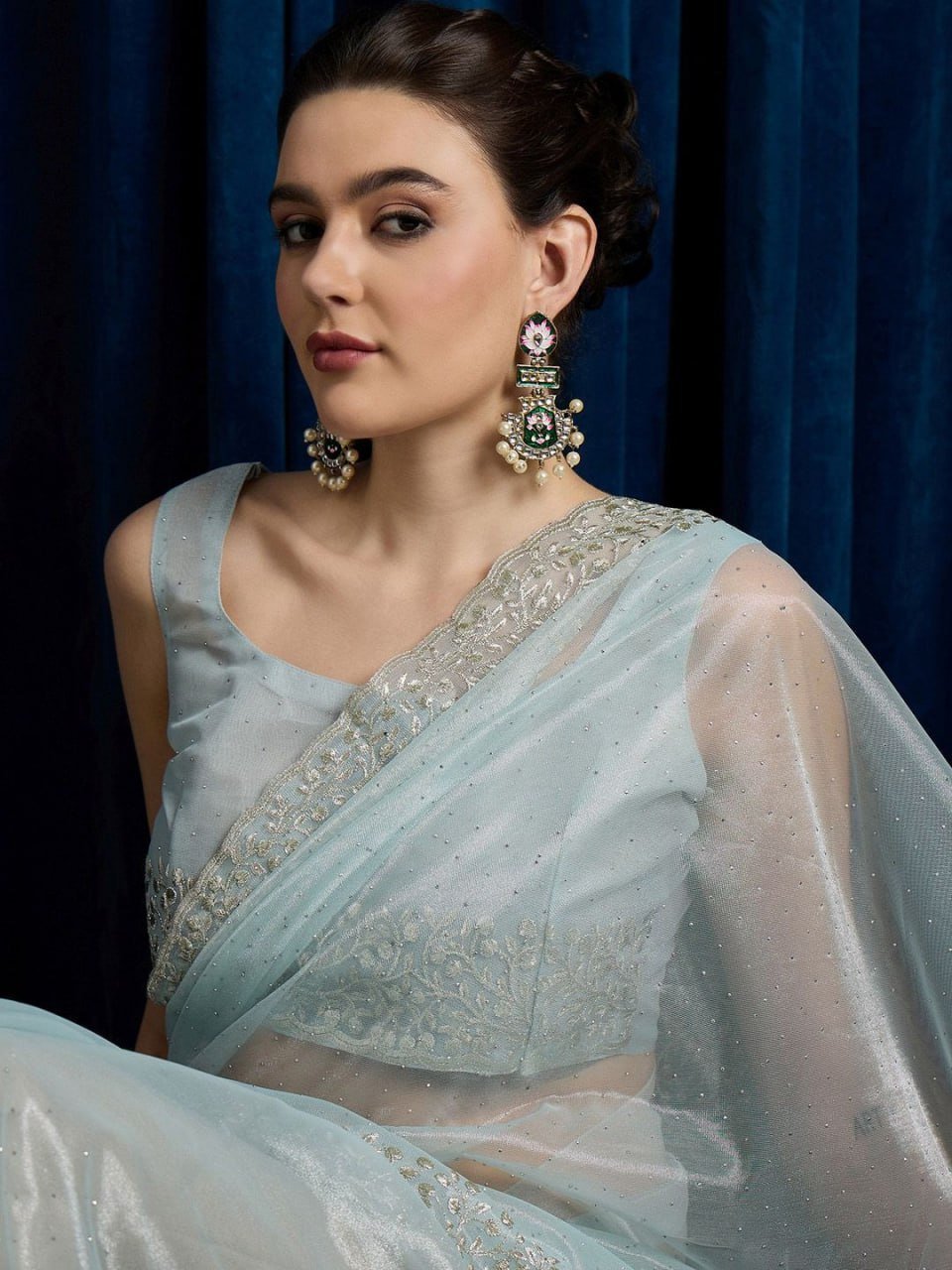 Close-up of sky blue net saree fabric with intricate cutwork and stone embellishment