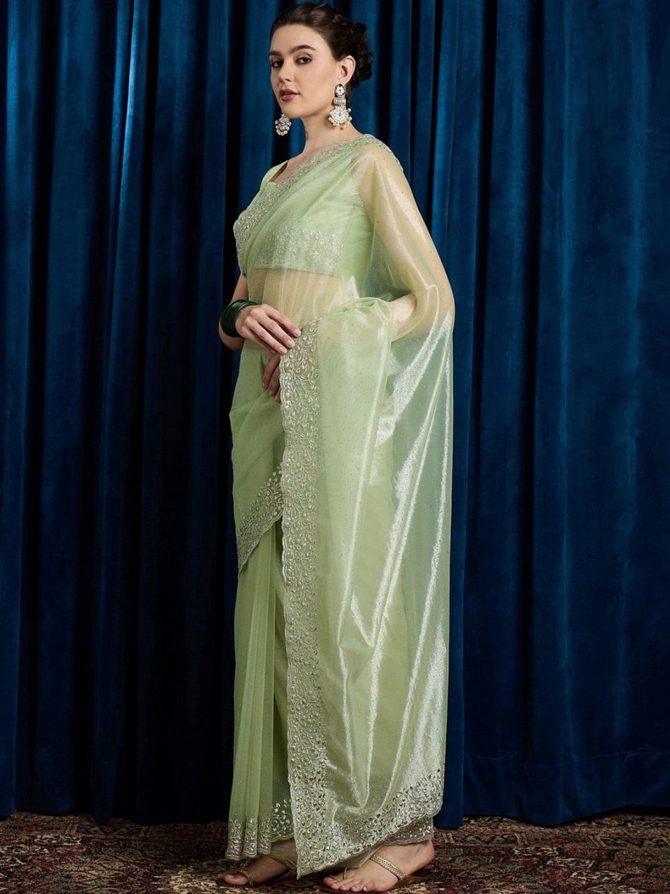 Woman wearing leaf green embellished hotfix cutwork net saree with beads and stones – party wear saree