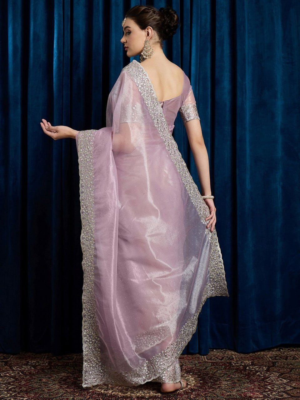 Close-up of pink net saree fabric with hotfix work, cutwork border, and stone embellishments