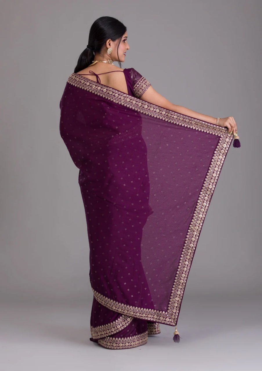 Woman wearing a purple saree with a plain background