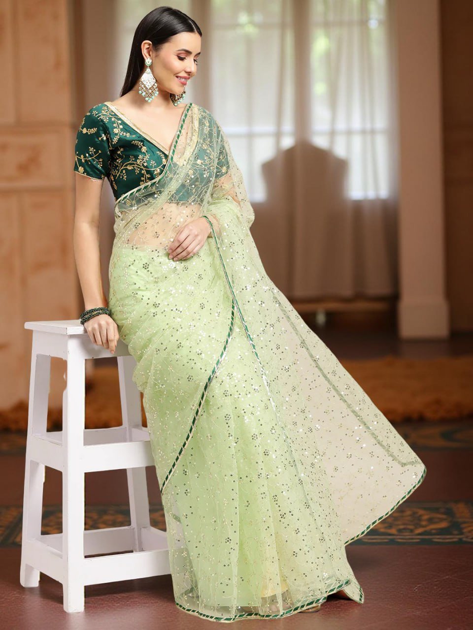 Close-up of pista green net saree fabric with embroidery and sequin work – designer saree detail